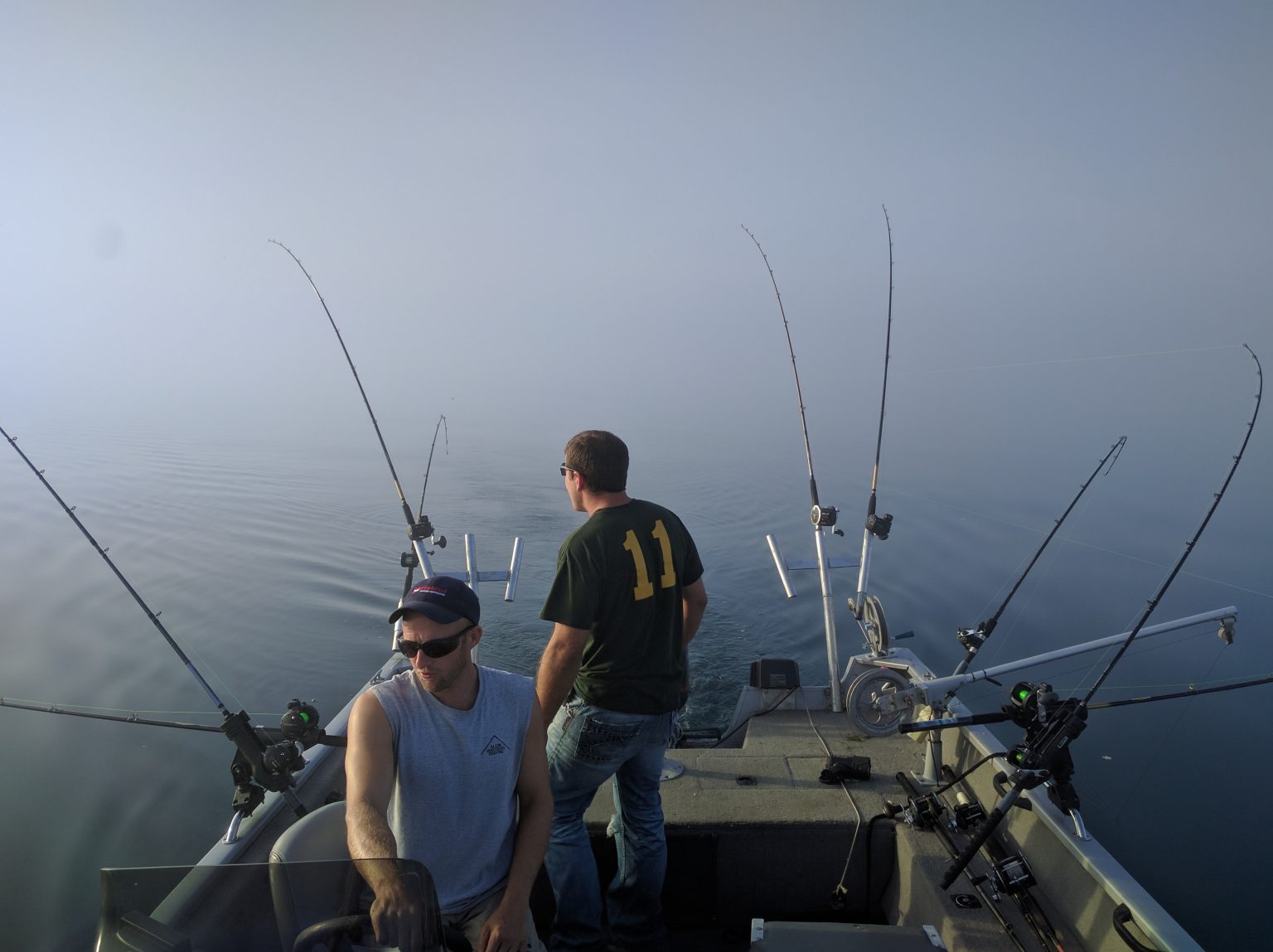 Two anglers working trolling rods on a foggy Lake Michigan morning