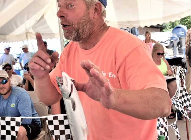 An angler telling a fish story under the tent at tournament weigh-in